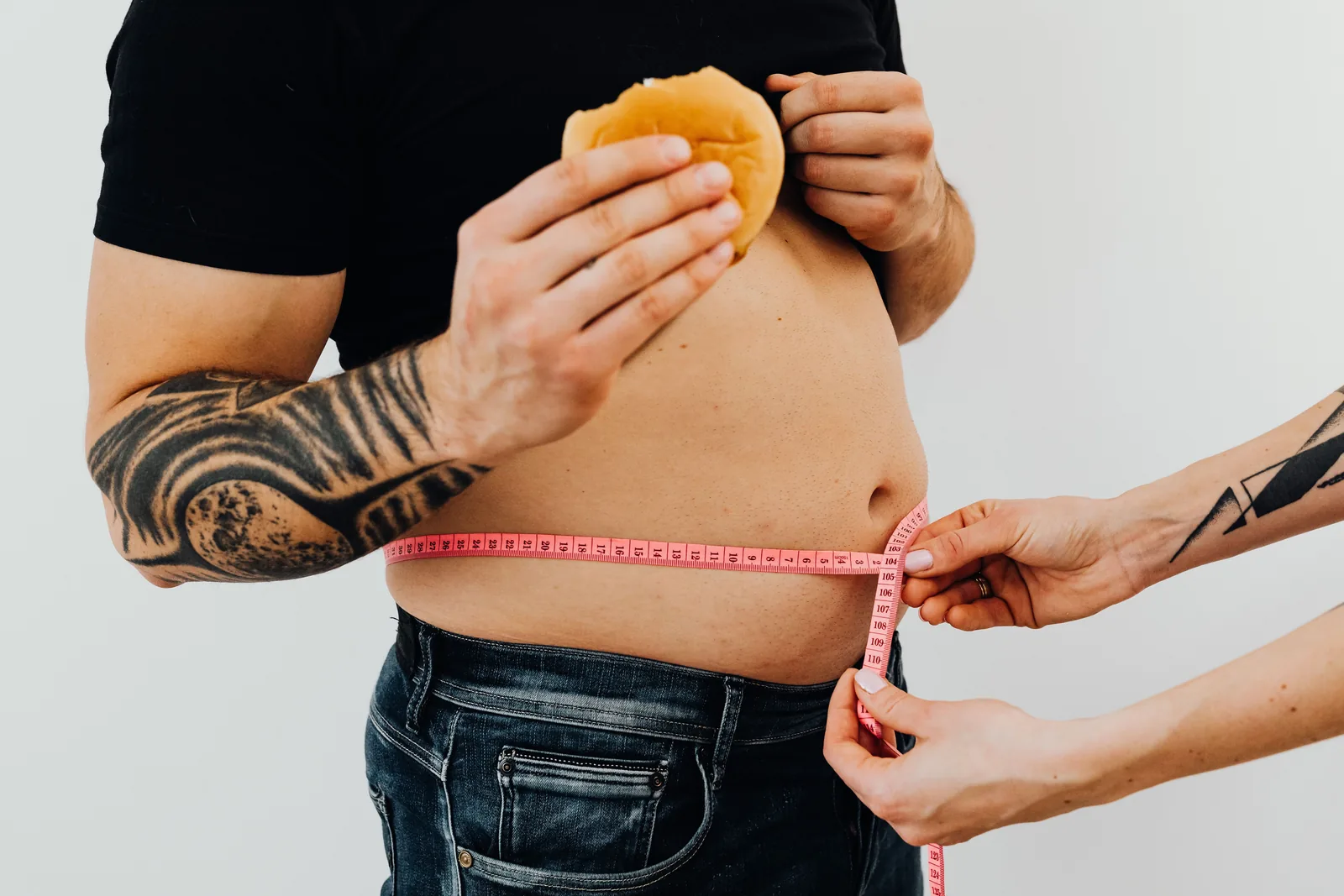 Someone measuring another person's waist with a tape measure
