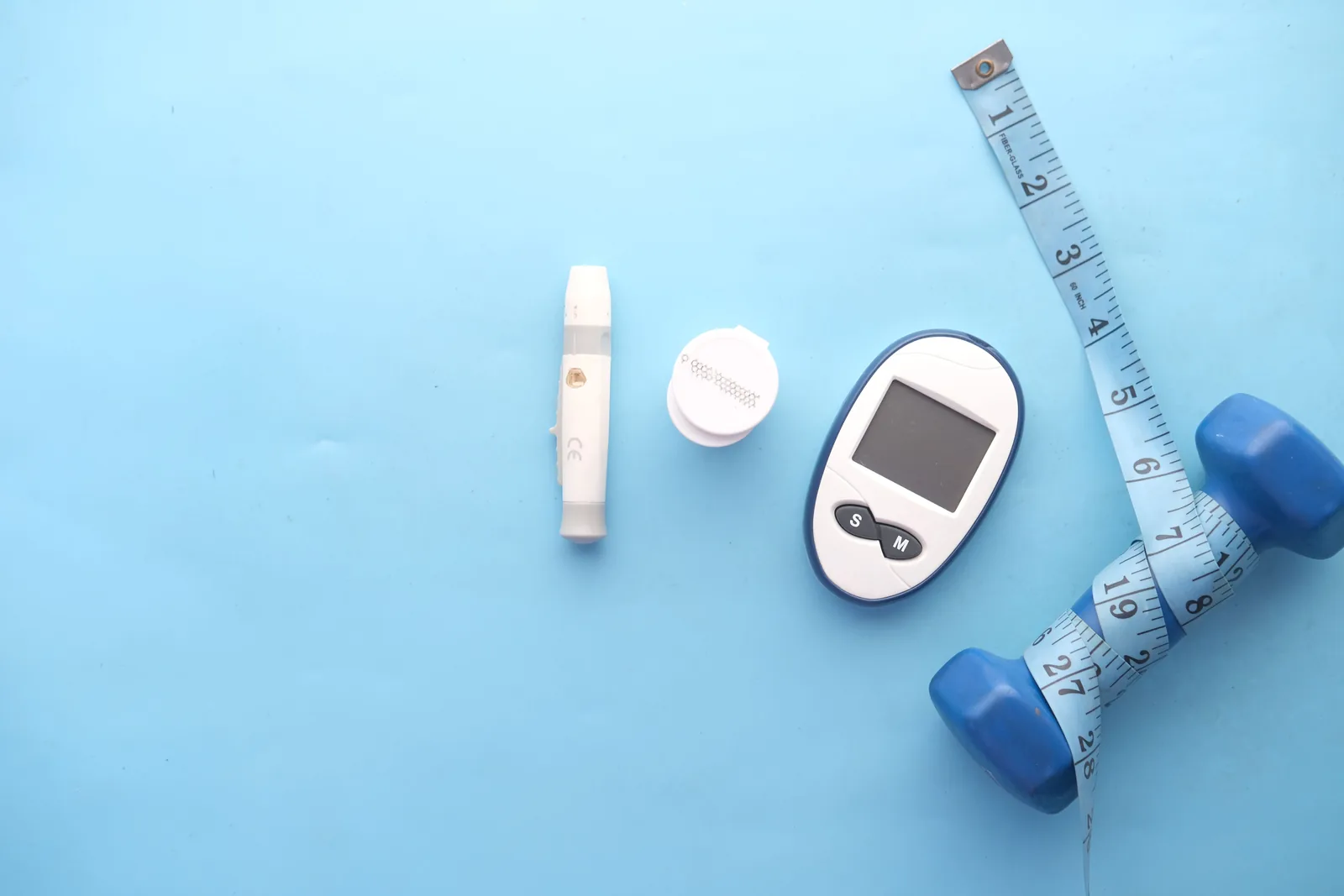 A blood glucose meter, tape measure and dumbbell