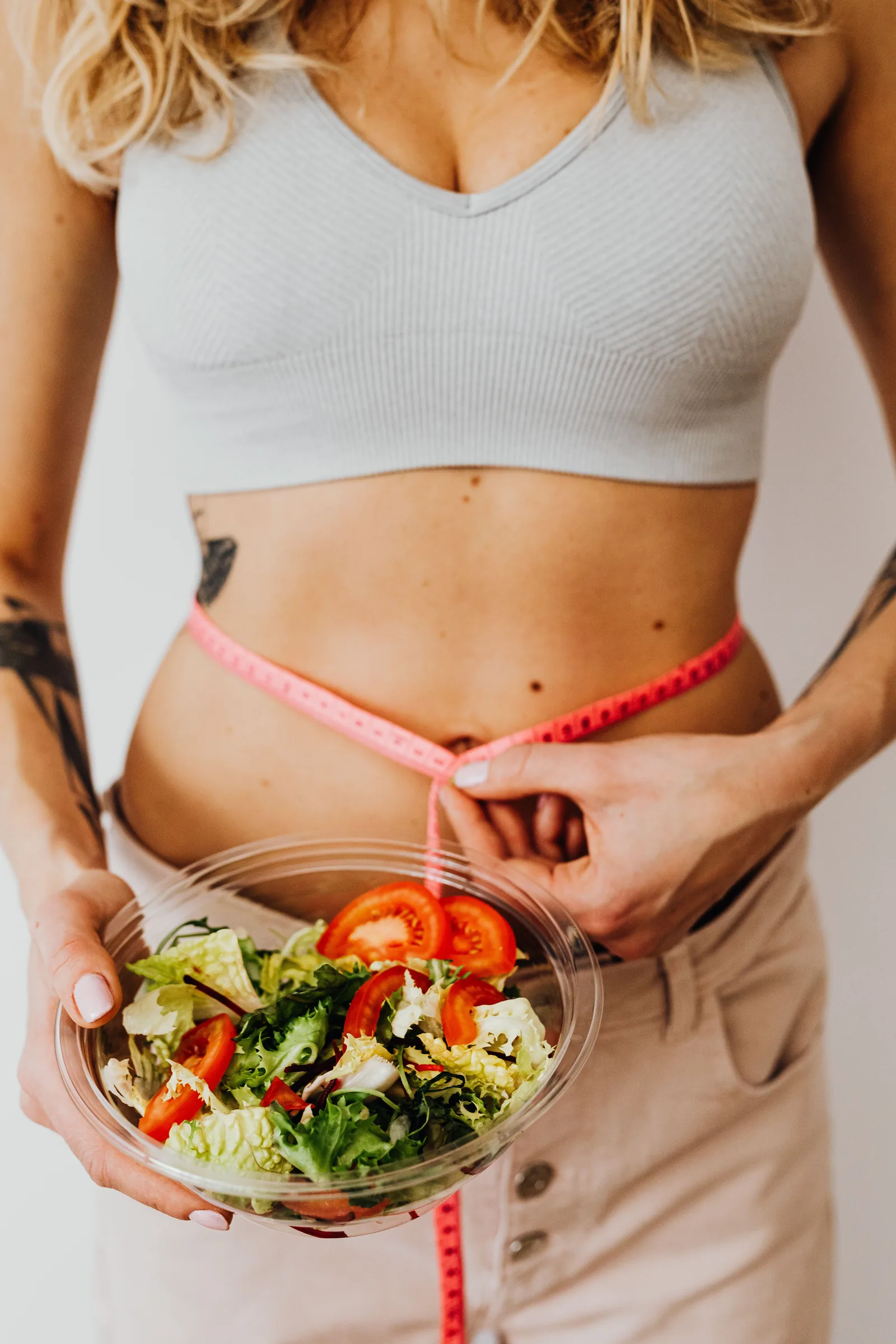 Holding a bowl of salad with a tape measure at the waist