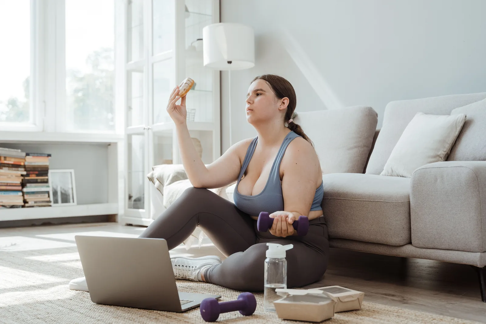 Exercising at home with a laptop, water and food to hand