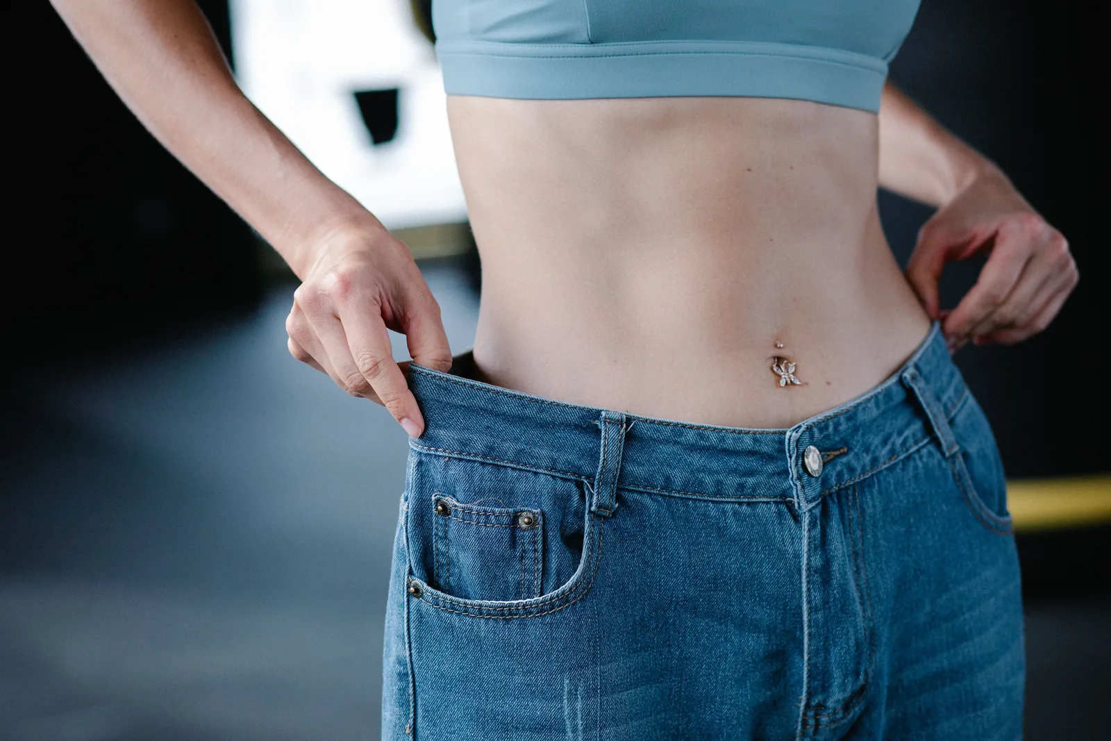 Oversized jeans held at the waist after weight loss