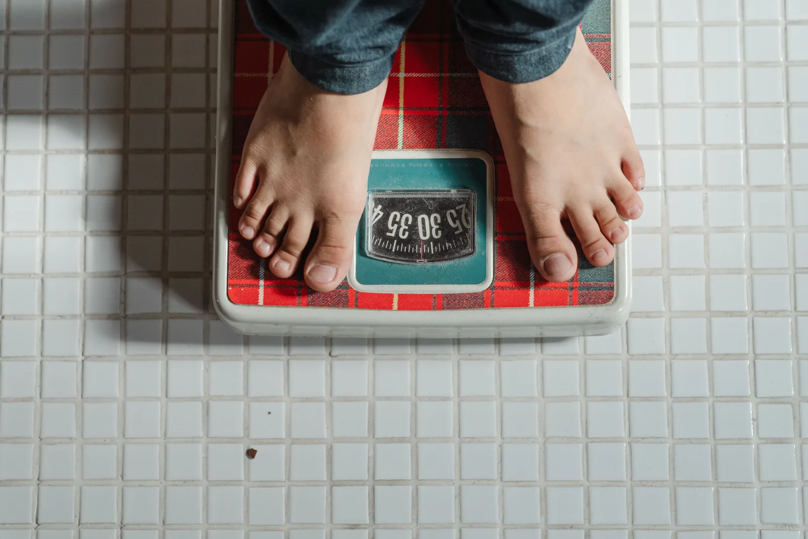 Standing on an older bathroom scale on a tiled floor